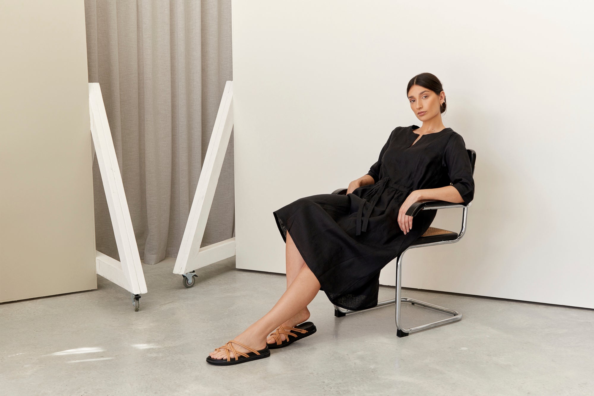 women wearing a long black linen dress with v neck detail, Nelle dress