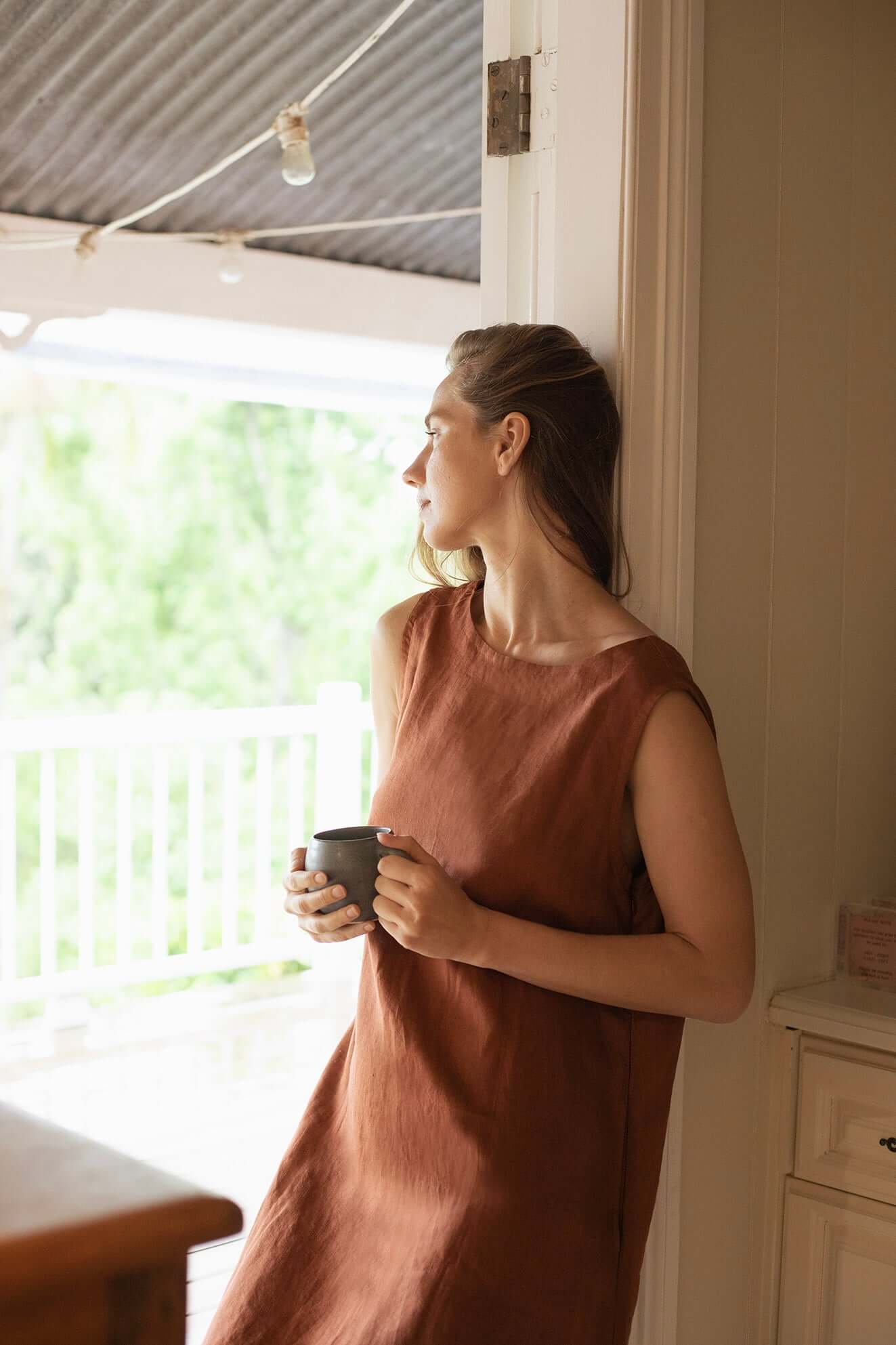 Woman wearing a Cynthia Linen Dress Bark, showcasing its versatile and elegant design.