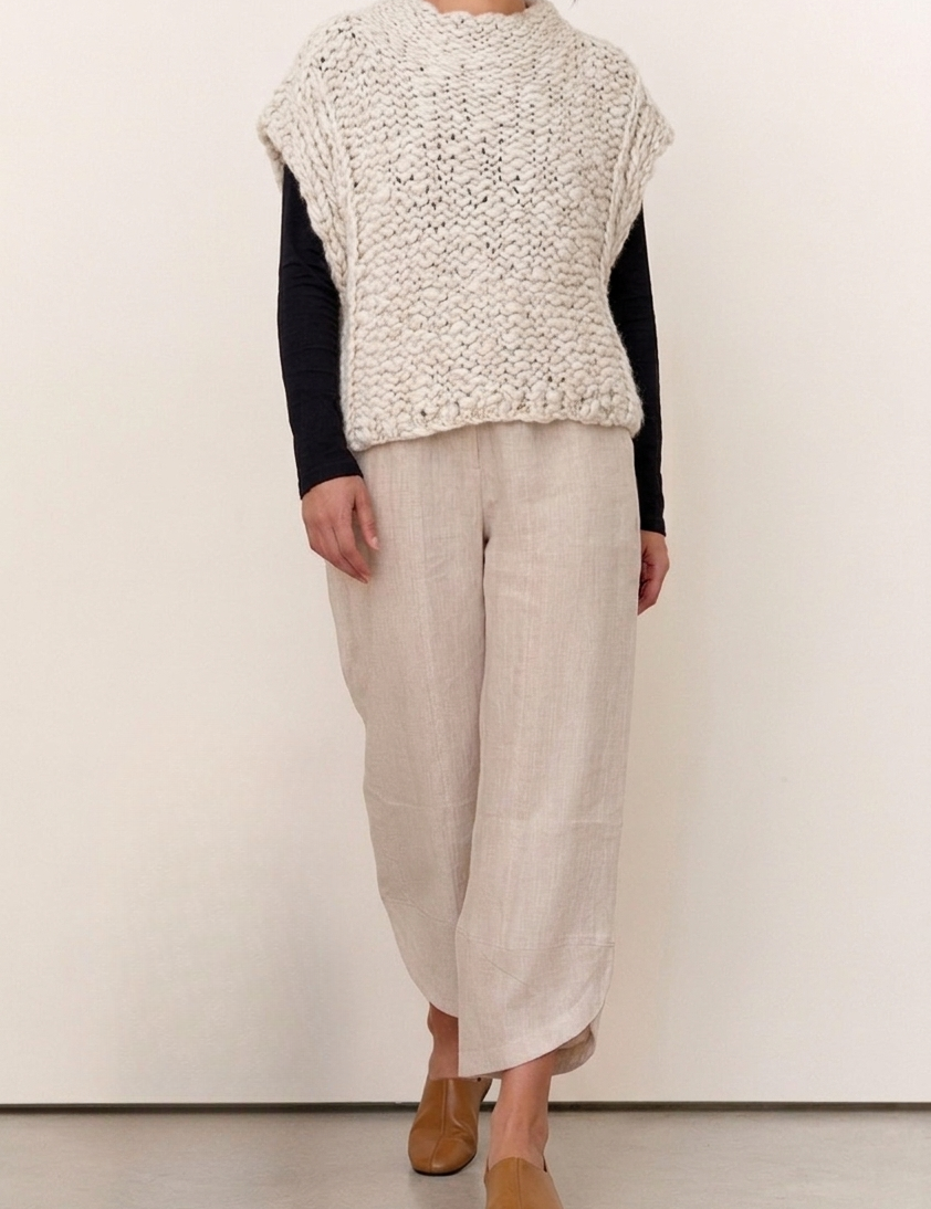 Model wearing the Harper Natural Textured Knit Vest over a long sleeve top, paired with light linen pants and tan shoes.