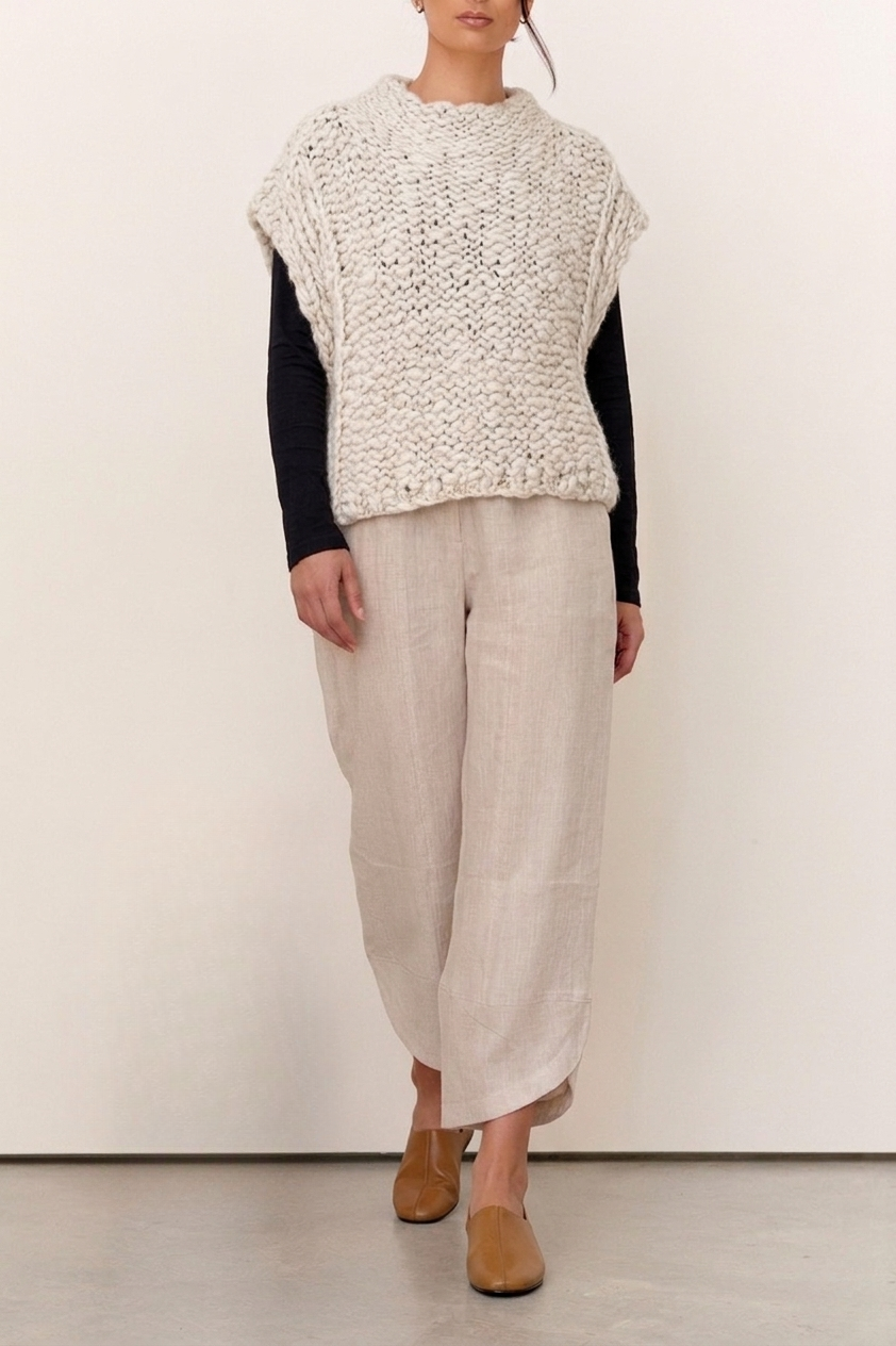 Model wearing the Harper Natural Textured Knit Vest over a long sleeve top, paired with light linen pants and tan shoes.