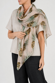 Woman wearing a beige scarf with pineapple pattern on a plain background