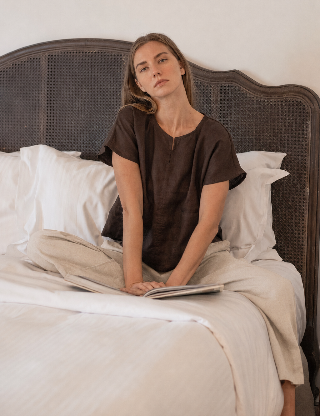 Model wearing Zoe Linen Top Cocoa whilst sitting on bed.