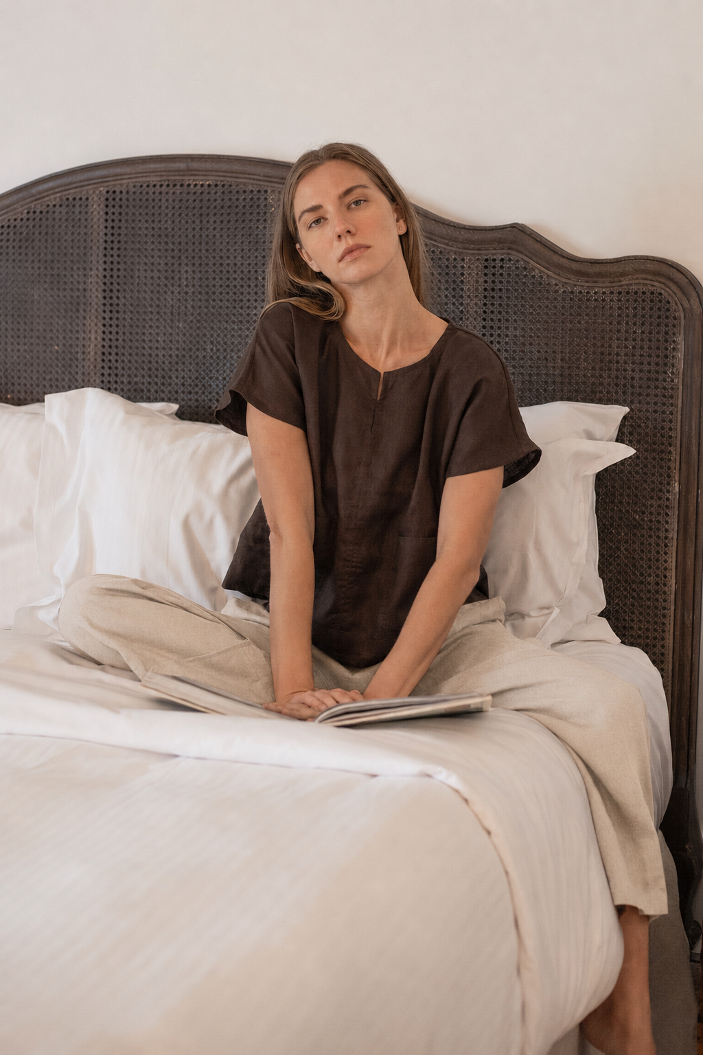 Model wearing Zoe Linen Top Cocoa whilst sitting on bed.
